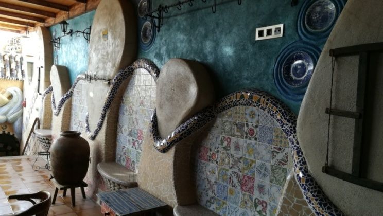 Pared de mosaico y piedra con banco incorporado y elementos decorativos, situada en el interior.