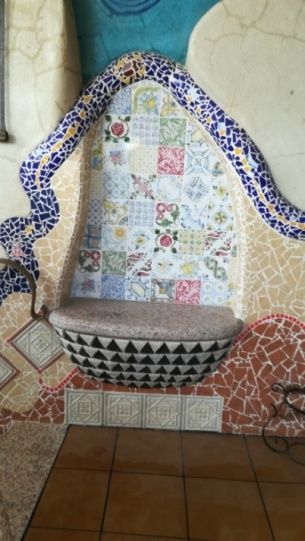 Banco de mosaico con estampados coloridos. Azulejos azules, blancos y marrones forman un respaldo curvo y una zona de asientos.