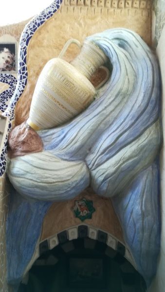 Figura esculpida sosteniendo una gran jarra, con remolinos de color azul y crema.