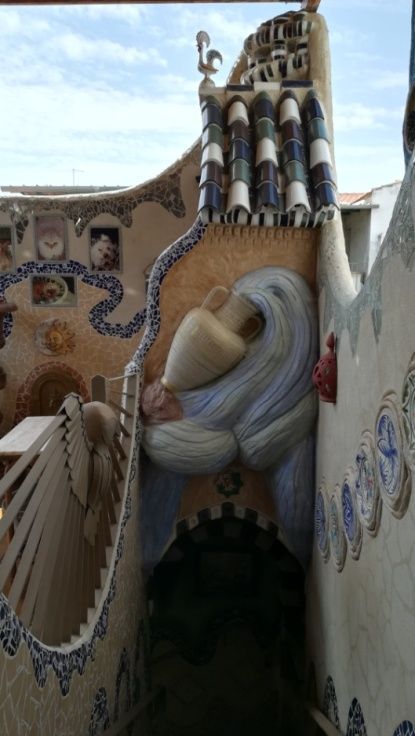 Detalle arquitectónico caprichoso: pared cubierta de mosaico con una cabeza de pájaro, arcos y azulejos estampados.