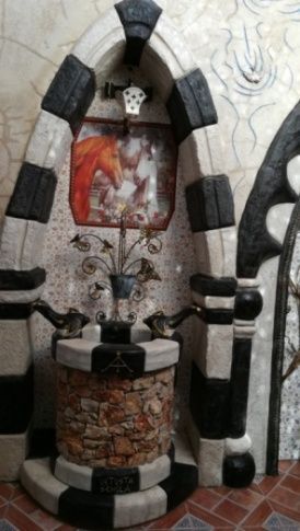 Pozo caprichoso con detalles en blanco y negro, que contiene una planta en maceta y una pintura de un zorro.