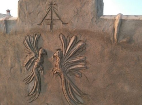 Muro con dos pájaros tallados y símbolo grabado.