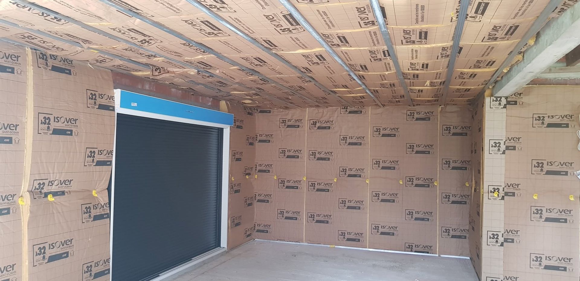 Pièce isolée en construction avec des panneaux de mousse rose et une grande ouverture de fenêtre.