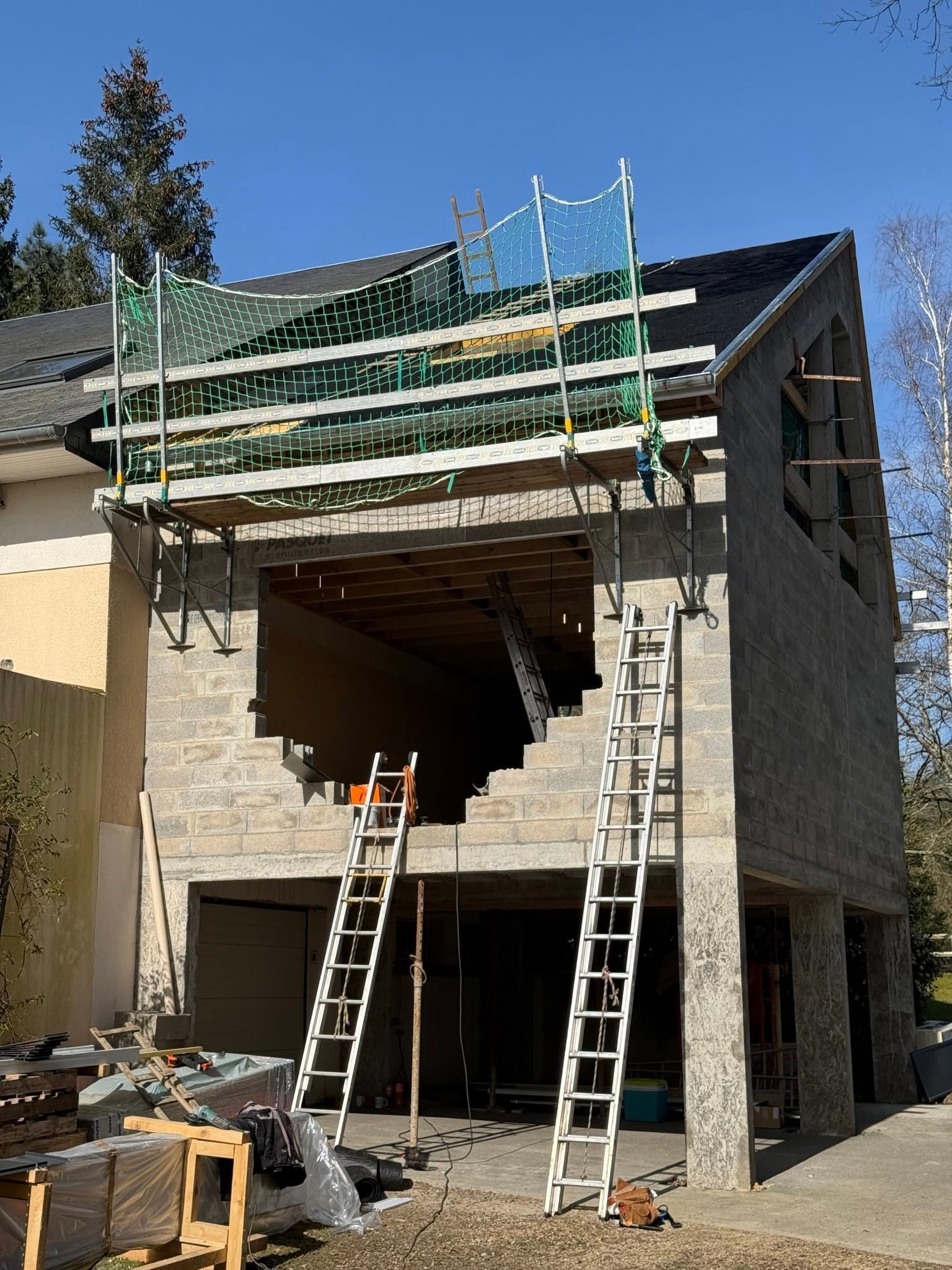 Maison en construction avec échafaudages et échelles sur la façade avant.