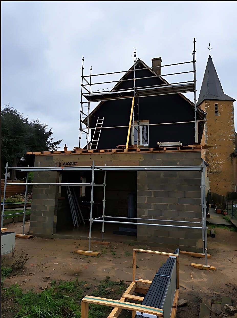 Maison en pierre en rénovation, avec échafaudages et toit pentu, vue depuis la cour.