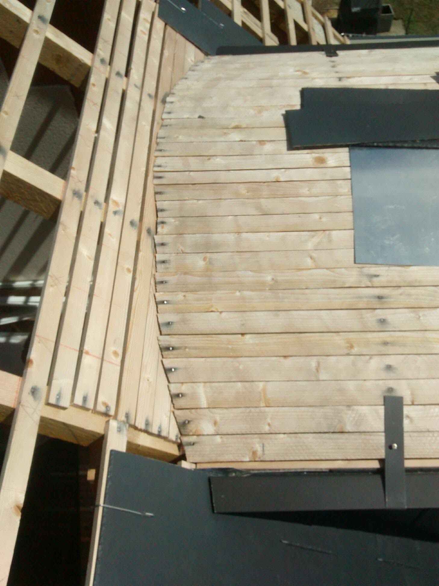Terrasse en bois à lattes incurvées et panneaux gris foncé, vue du dessus.