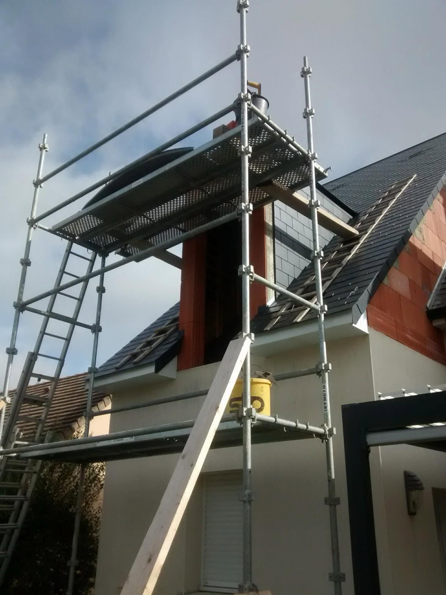 Échafaudages autour du toit et de la lucarne d'une maison lors de travaux de réparation extérieure.