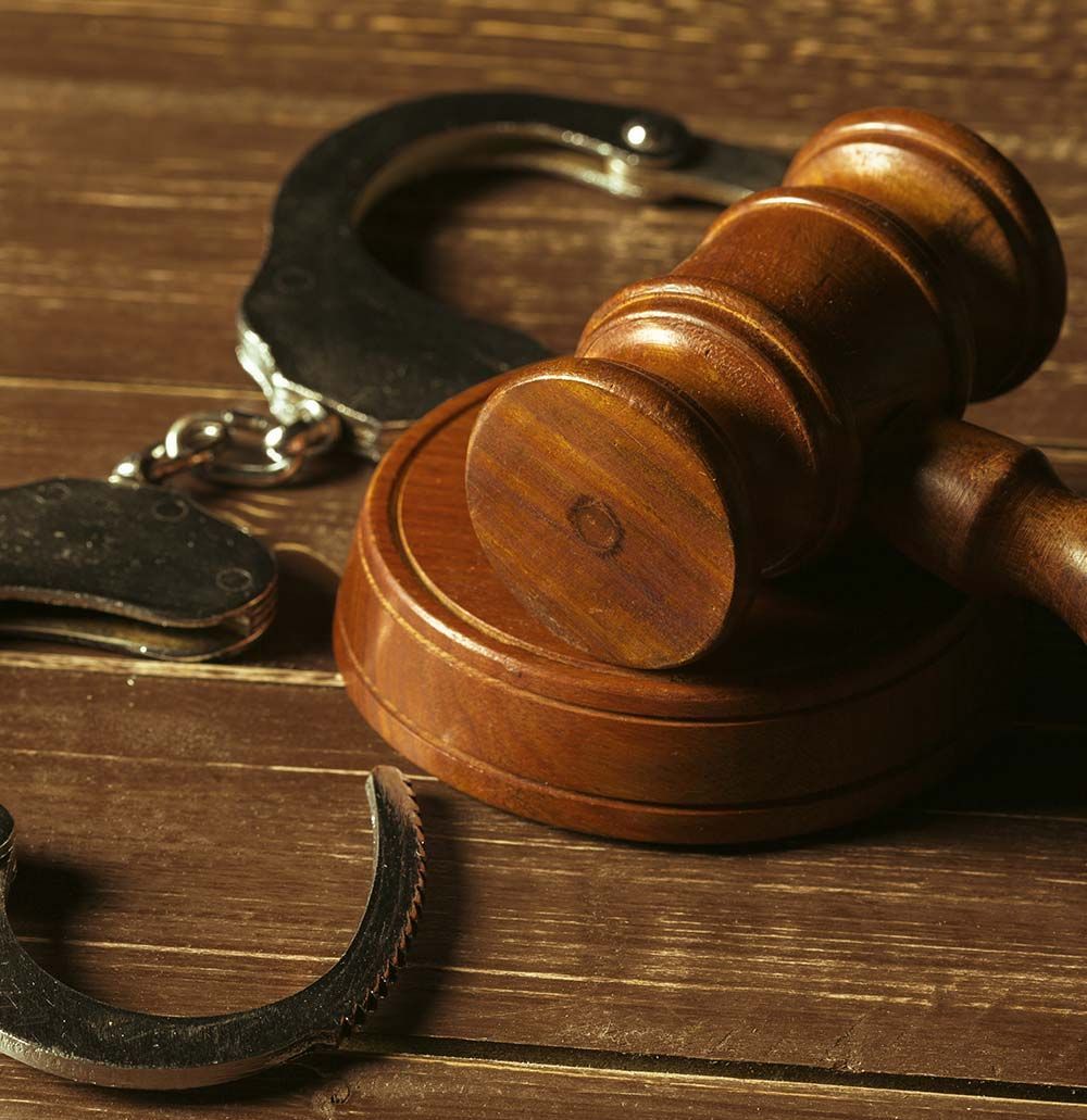 Mazo de madera y esposas sobre una superficie de madera, representando el sistema de justicia.