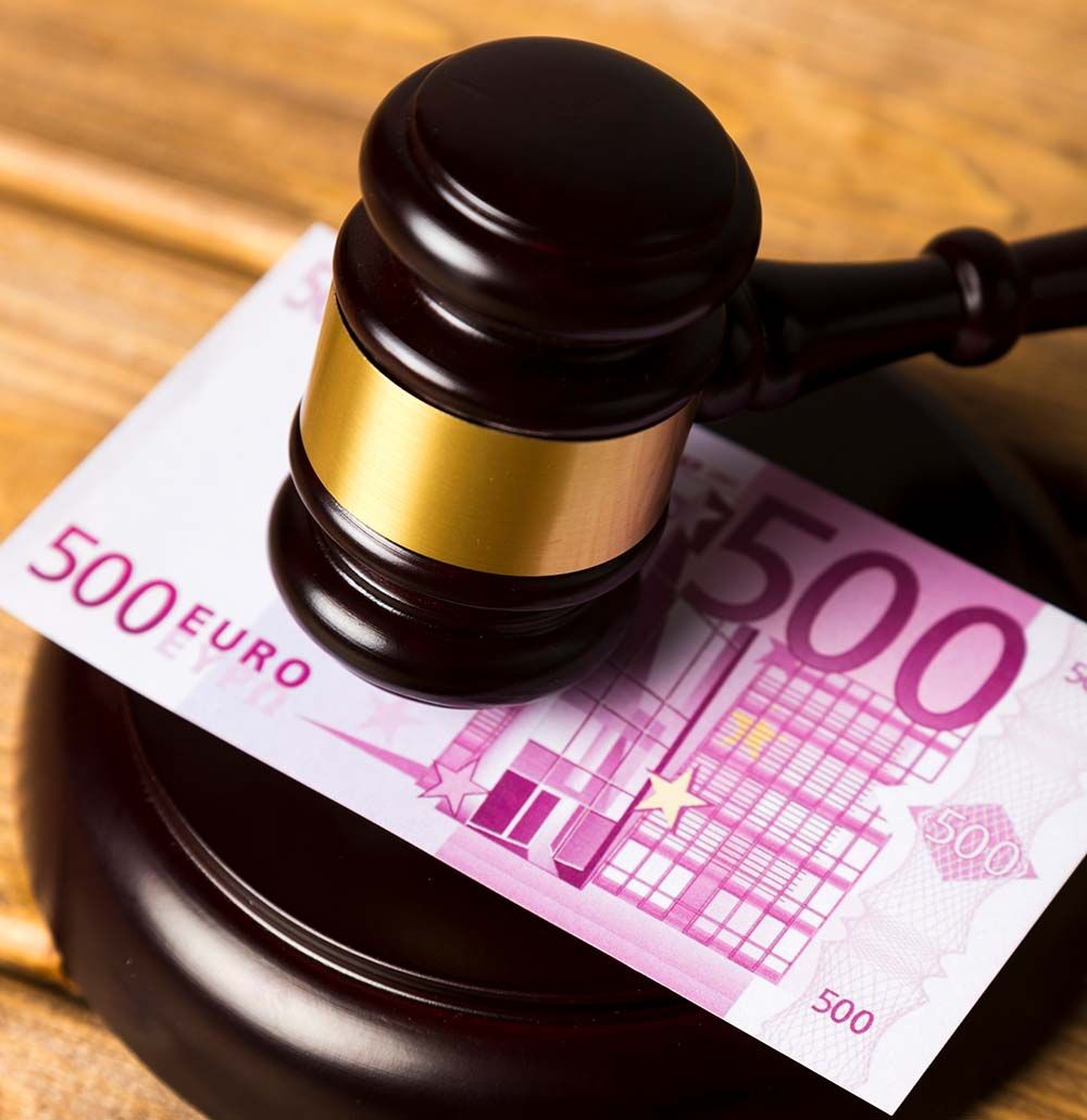 Martillo apoyado sobre un billete de 500 euros, lo que sugiere un contexto legal o financiero.