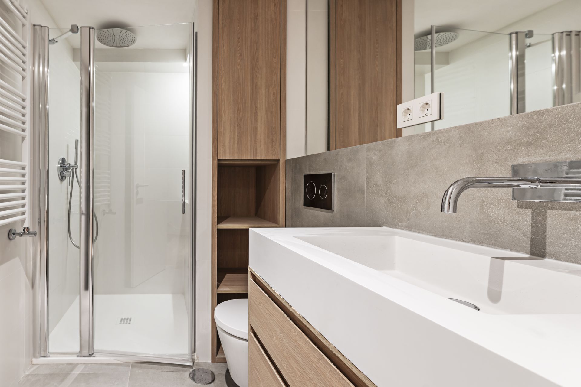 Modernes, dunkles Badezimmer mit türkisfarbenem Waschtisch, rundem Spiegel und schwarzer Toilette.