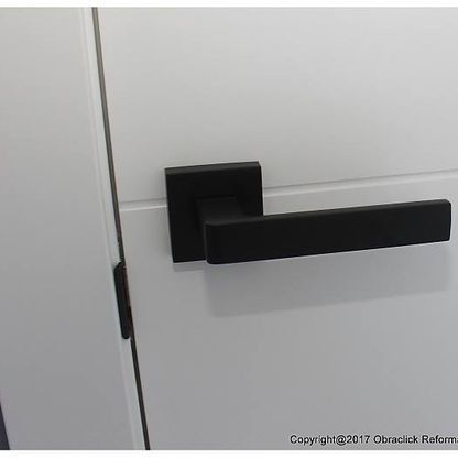Un primer plano de una manija de puerta negra en una puerta blanca.