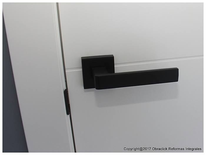 Un primer plano de una manija de puerta negra en una puerta blanca.