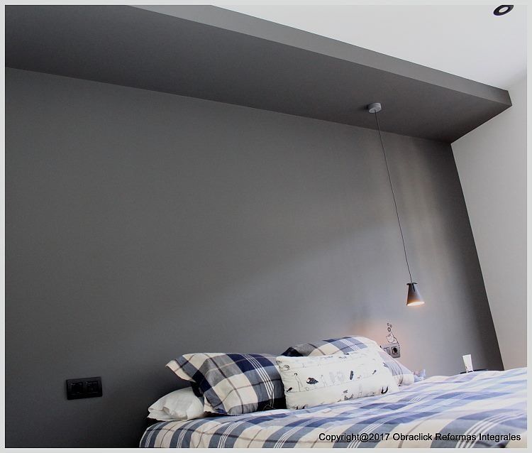 Un dormitorio con una cama y una lámpara colgando del techo.