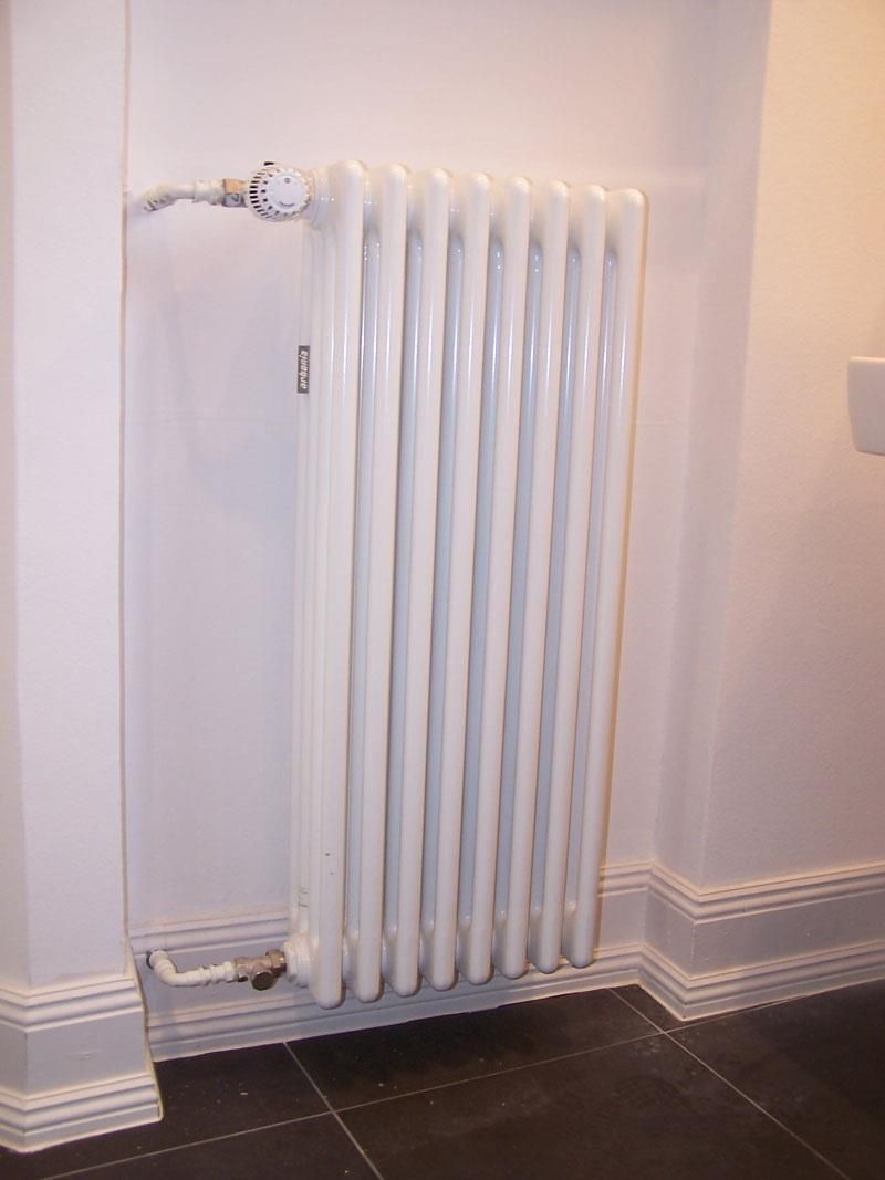 Ein weißer Heizkörper ist an einer weißen Wand montiert