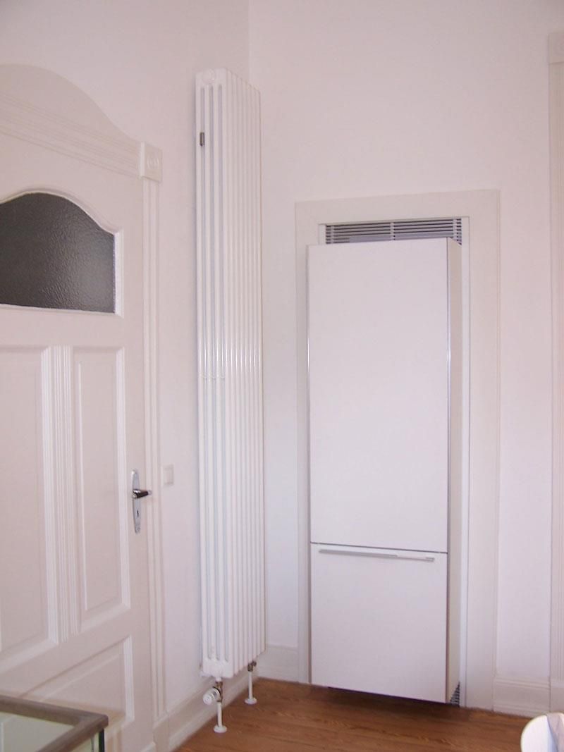 Ein Raum mit einem weißen Kühlschrank und einem weißen Heizkörper