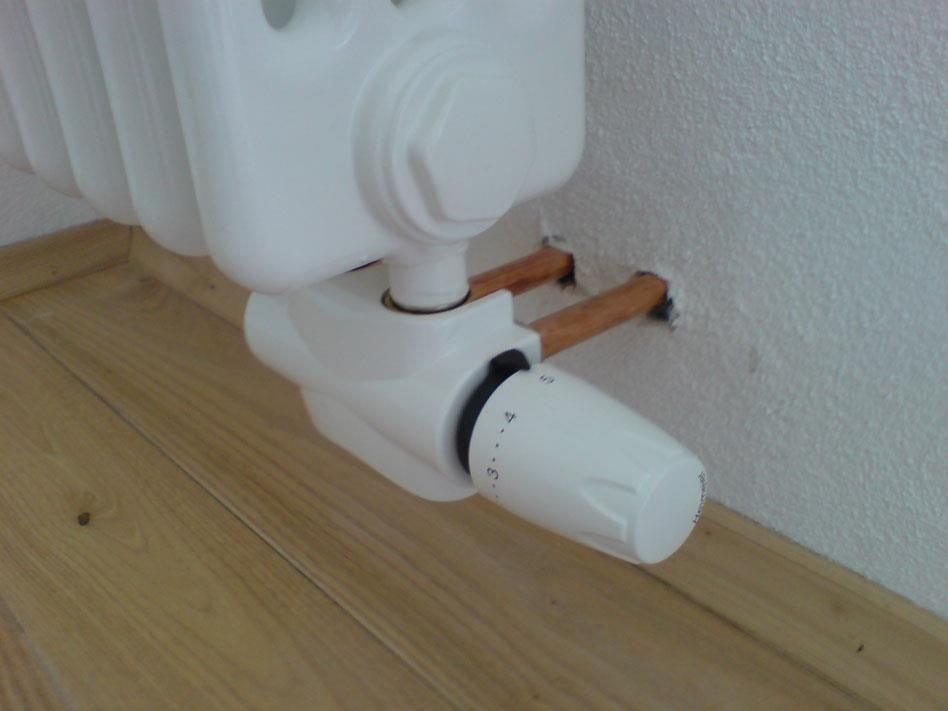 Ein weißer Heizkörper mit einem daran befestigten Thermostat