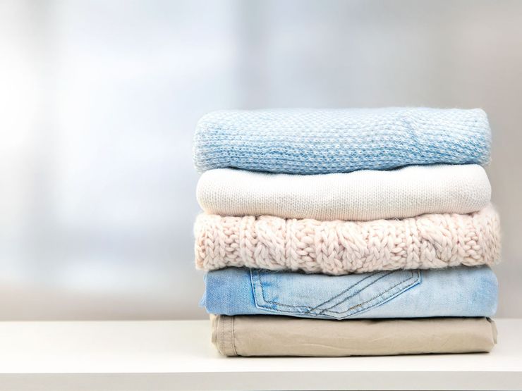 Une pile de vêtements pliés sutr une table.