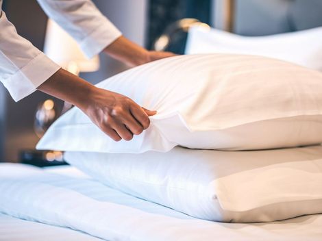 Une personne qui est en train de poser un oreiller sur le lit.