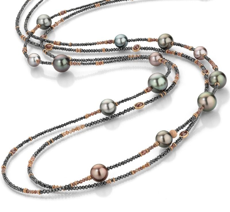 Eine mehrreihige Perlenkette mit dunkelgrauen Perlen und kupferfarbenen Metallperlen auf weißem Grund.