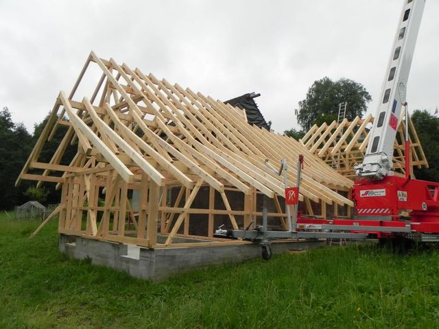 Blick von oben auf eine Holzterrasse mit grauem Esstisch und Stühlen, die sich vor einem Gebäude mit Glastüren befindet.