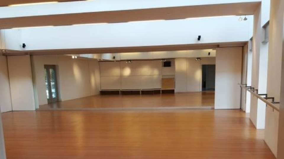 Eine von oben gesehene Holztreppe mit weißen Stufen und Glasgeländer blickt hinunter in eine moderne, hell erleuchtete Lobby.