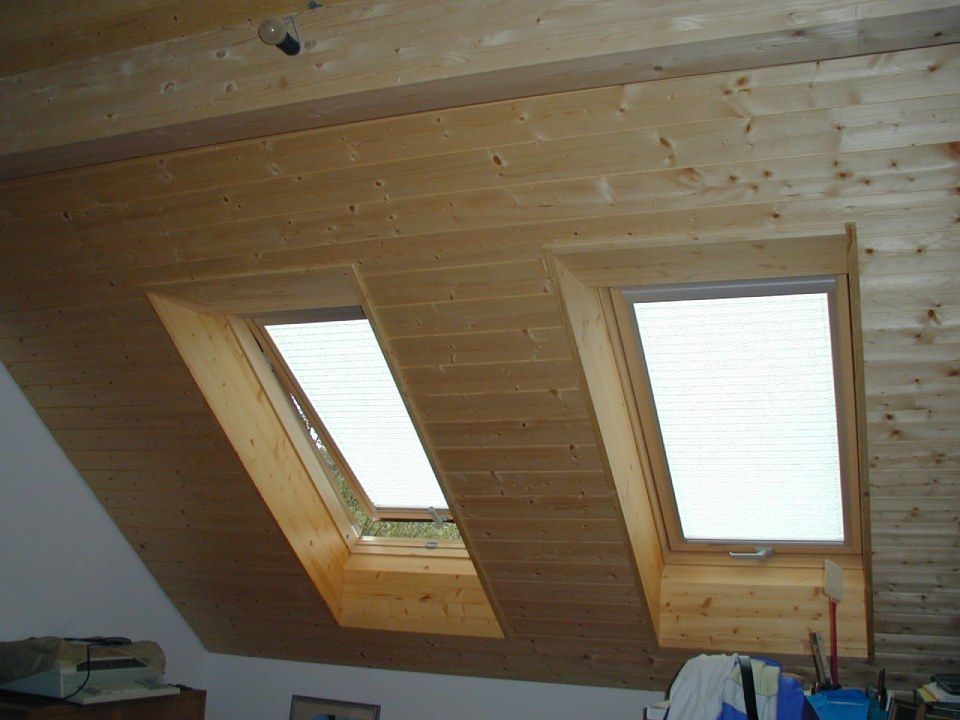 Zwei Dachfenster in einer hellen, schrägen Holzdecke in einem Dachzimmer.