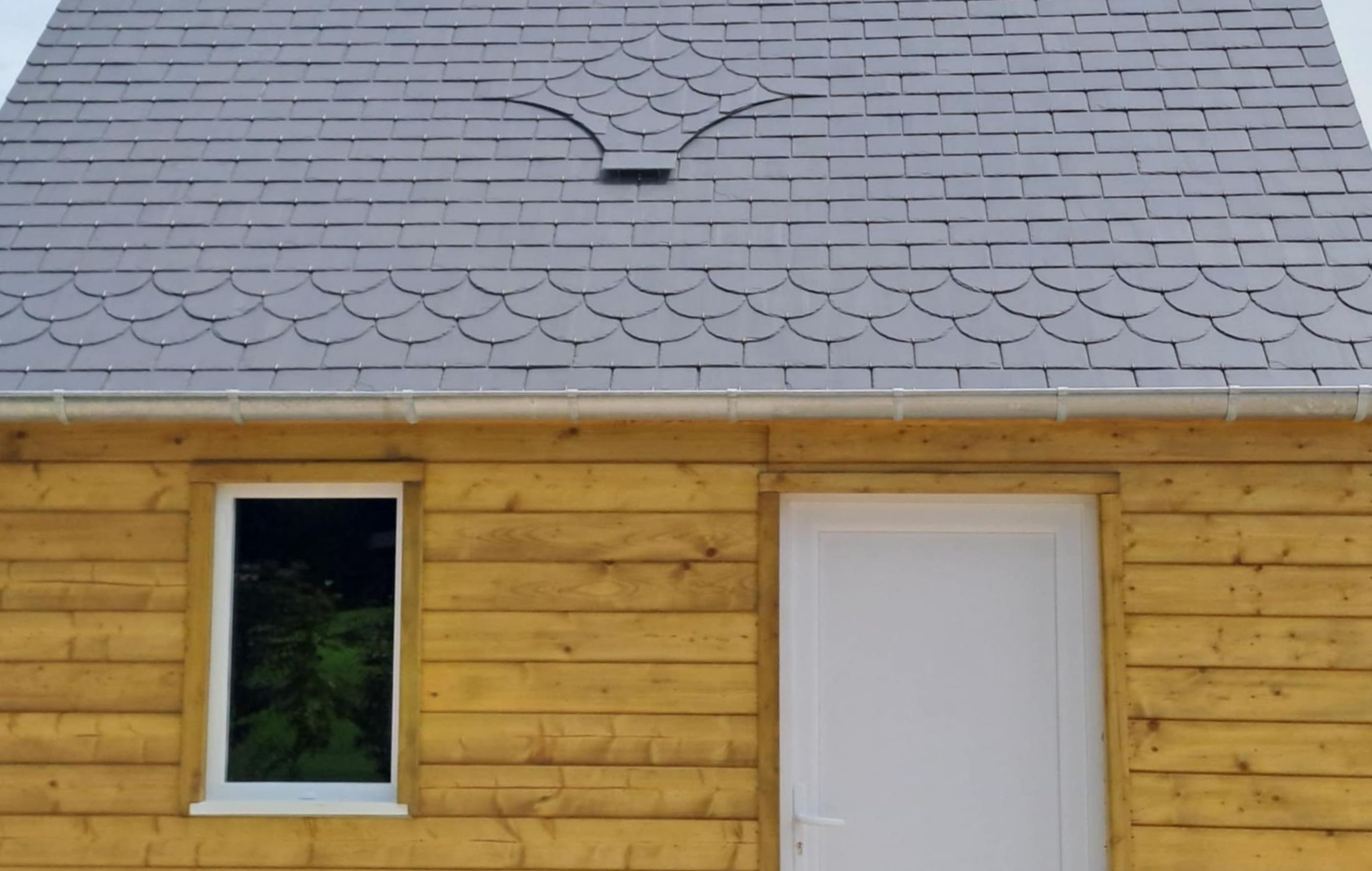 Extérieur du bâtiment avec échafaudages et balcons ; ouvrier du bâtiment sur un échafaudage ; façade brun clair et blanc.