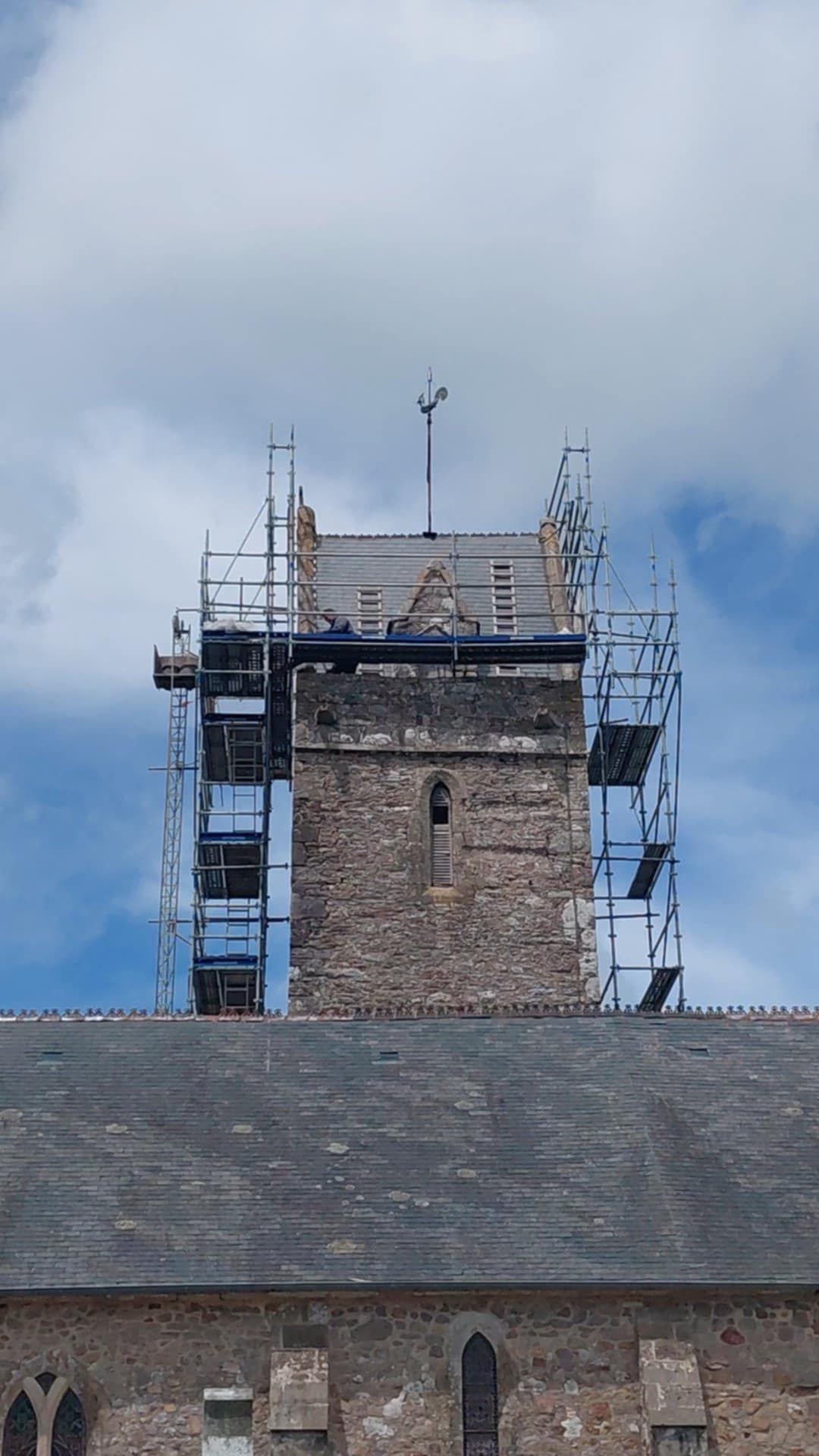 Clocher d'église avec échafaudages, en cours de réparation ; ciel bleu en arrière-plan.