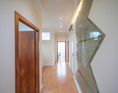 Pasillo largo con suelo y puertas de madera. Una pared tiene un gran espejo.