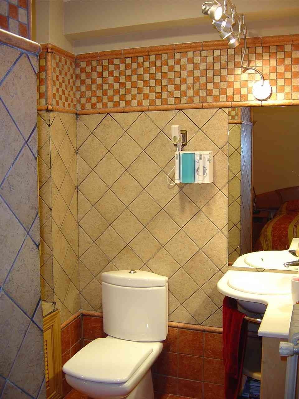 Baño pequeño con inodoro, lavabo y paredes y suelo de azulejos beige.