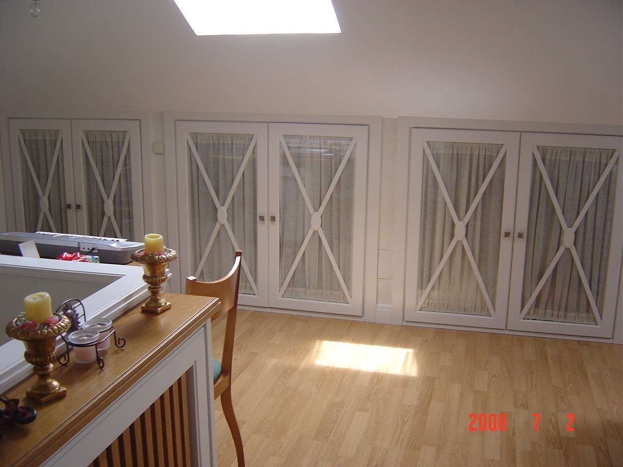 Comedor luminoso con armarios blancos, suelo de madera y luz natural que entra por las ventanas.
