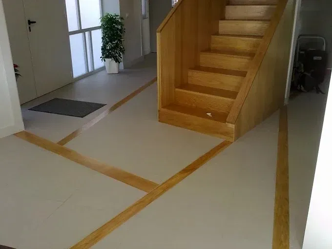 Escalera interior con marcas en el suelo y una planta en maceta cerca de la entrada.