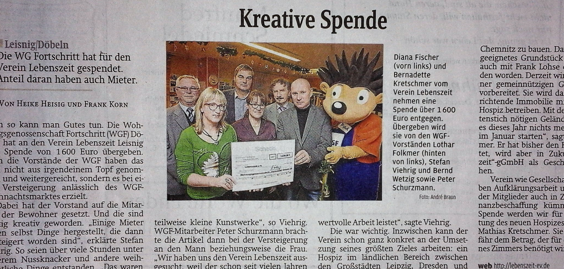 Ein Zeitungsartikel mit dem Titel „Kreative Spende“, der eine Gruppe von Menschen mit einem großen Spendenscheck zeigt.
