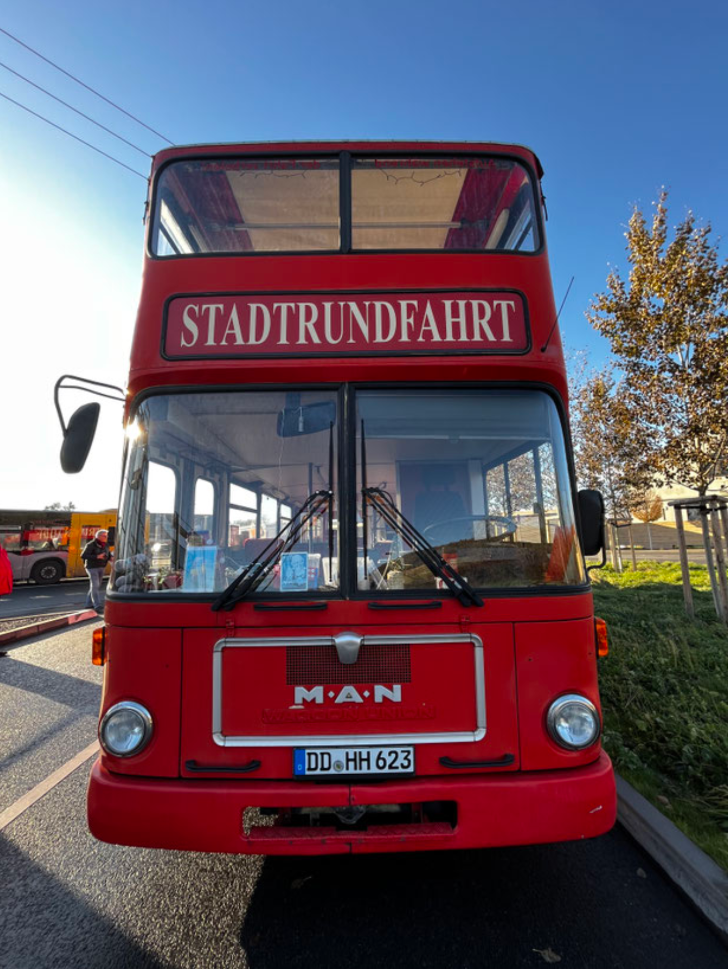Ein roter MAN-Doppeldeckerbus mit der Aufschrift „STADTRUNDFAHRT“ an der Front, der an einem sonnigen Tag im Freien parkt.