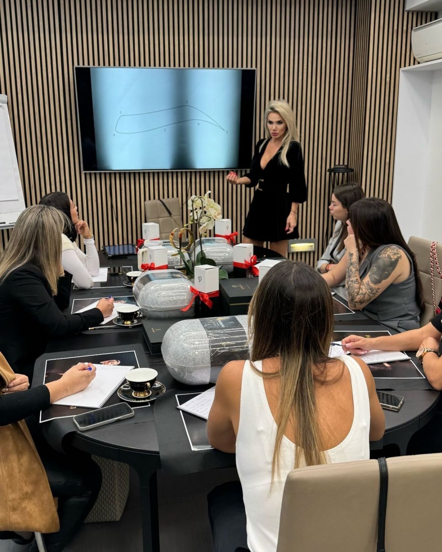 Un grupo de mujeres está sentada alrededor de una mesa en una sala de conferencias.