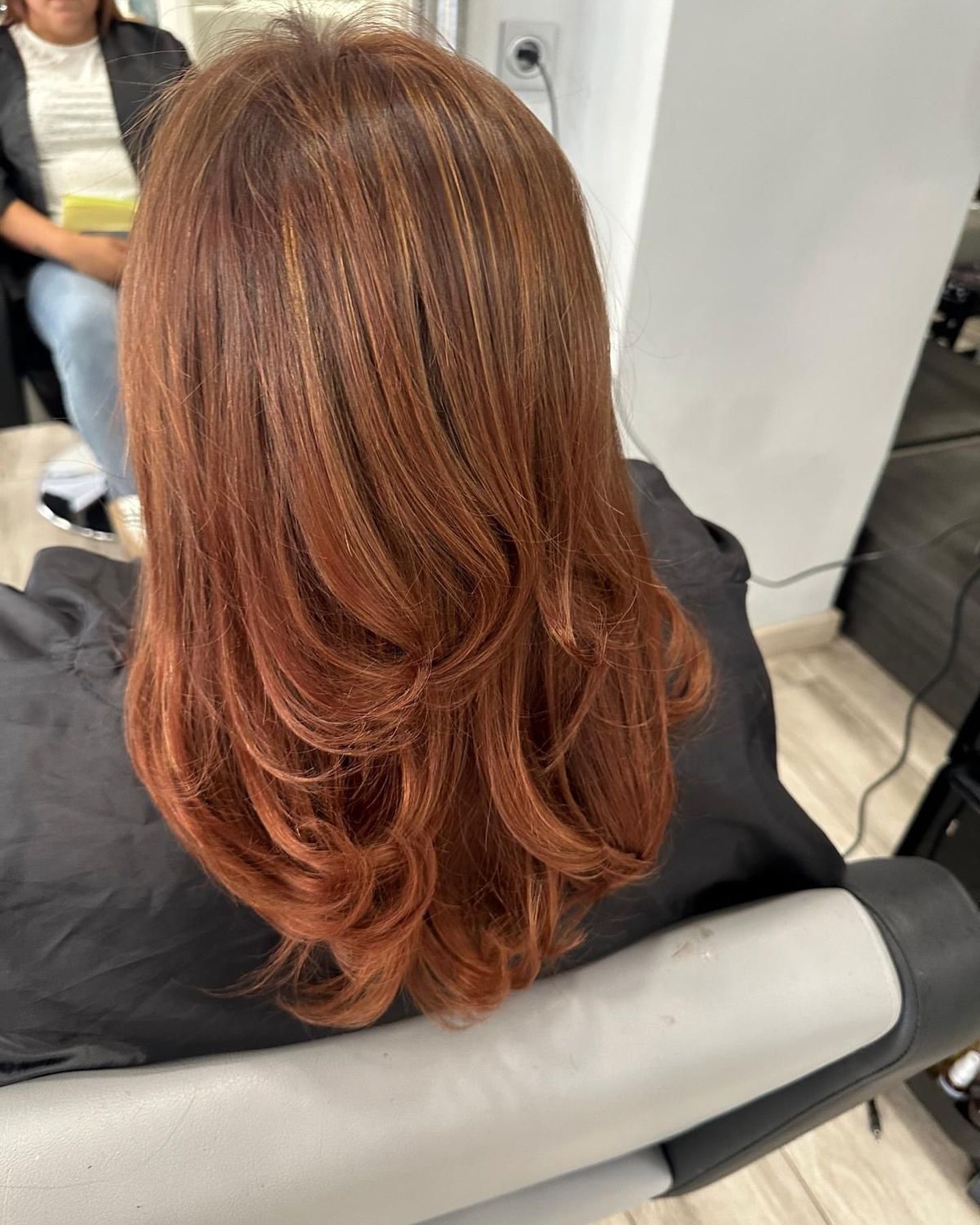 Una mujer con cabello rojo está sentada en una silla en un salón.