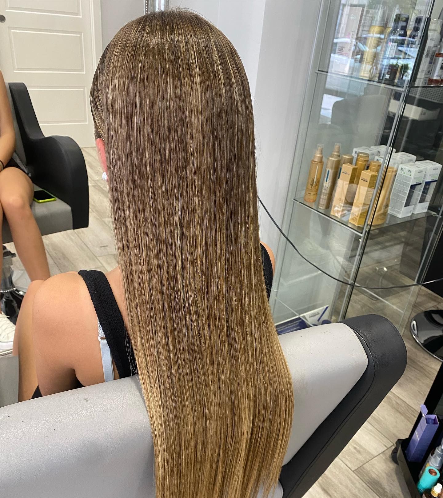 Una mujer con cabello largo está sentada en una silla en un salón.