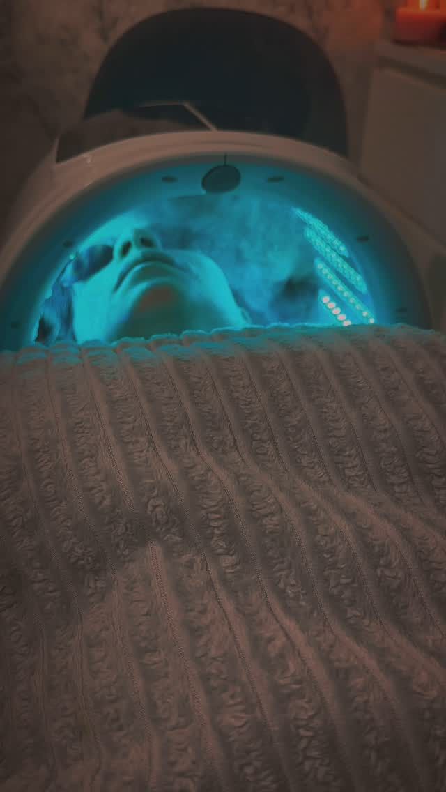 Una persona está acostada en una cama con una luz azul en su cara.