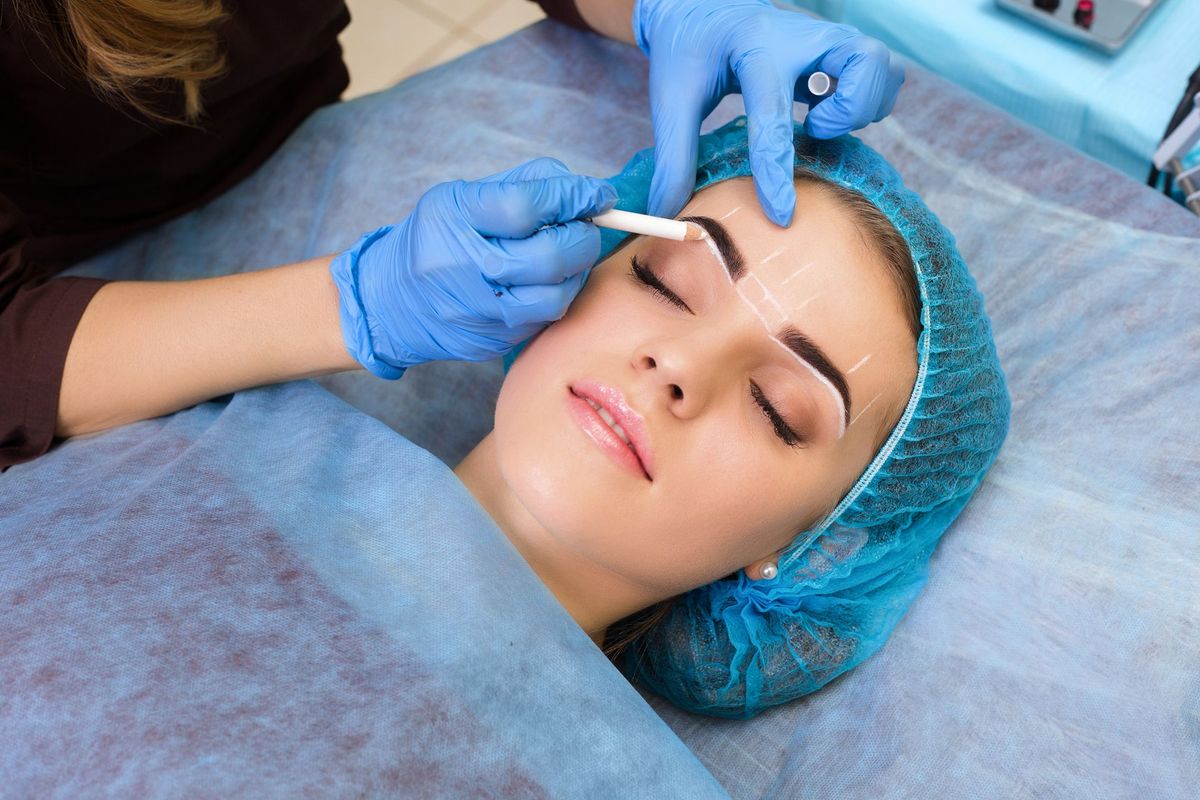 Una mujer se está tatuando las cejas en un salón de belleza.