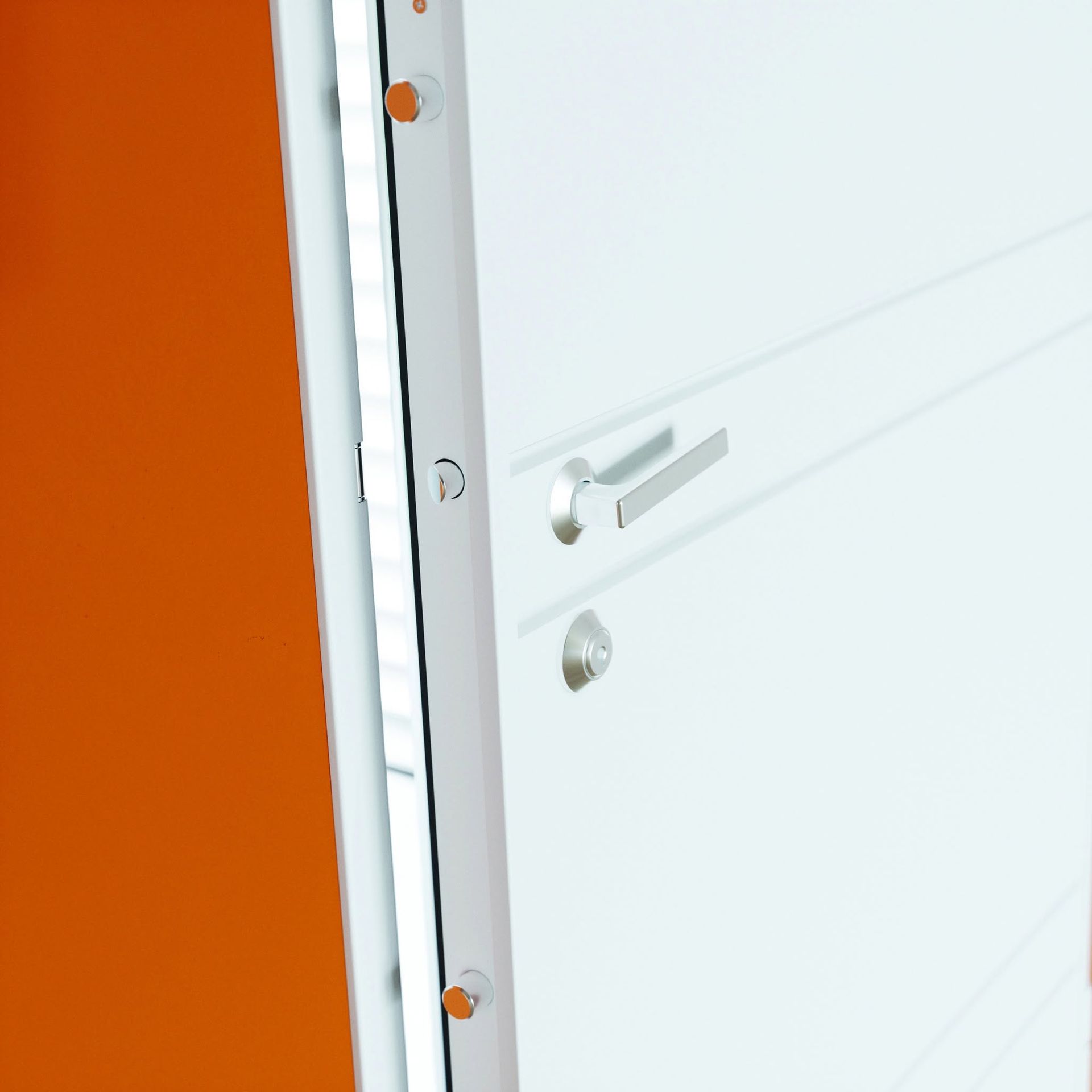 Porte blanche avec poignée légèrement ouverte à côté d'un mur orange