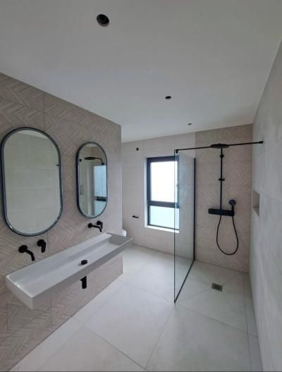 Salle de bains moderne avec lavabo suspendu, miroirs ronds et paroi de douche en verre avec robinetterie noire