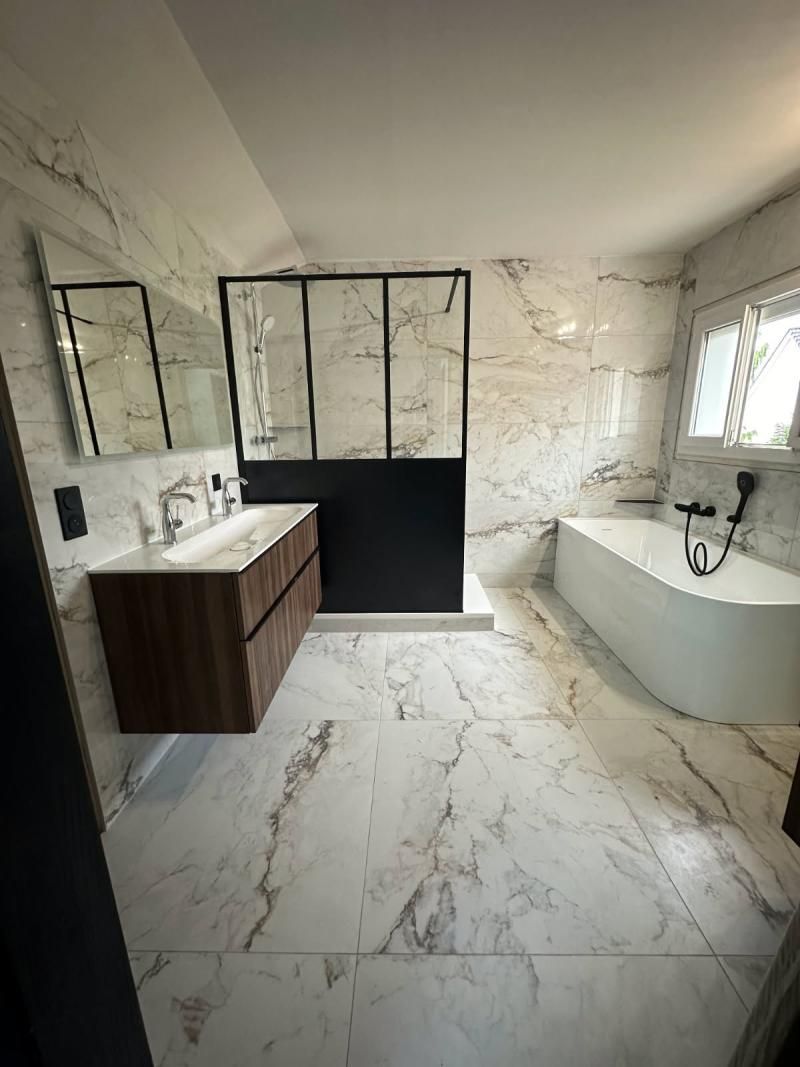 Salle de bains moderne avec murs et sol en marbre, meuble-lavabo en bois, douche à cadre noir et baignoire îlot