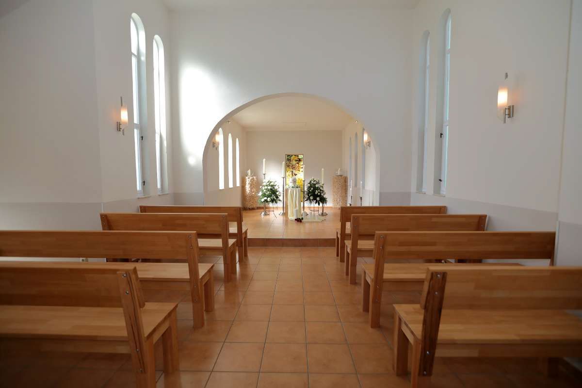 Eine leere Kirche mit Holzbänken und einem Podium in der Mitte.