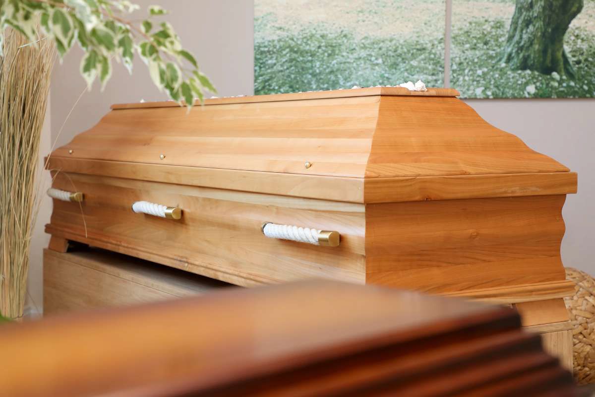 Ein Holzsarg steht auf einem Holztisch in einem Raum.