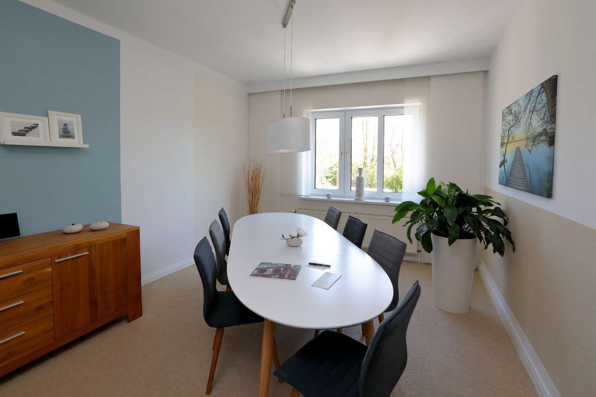 Ein Esszimmer mit einem langen weißen Tisch und Stühlen