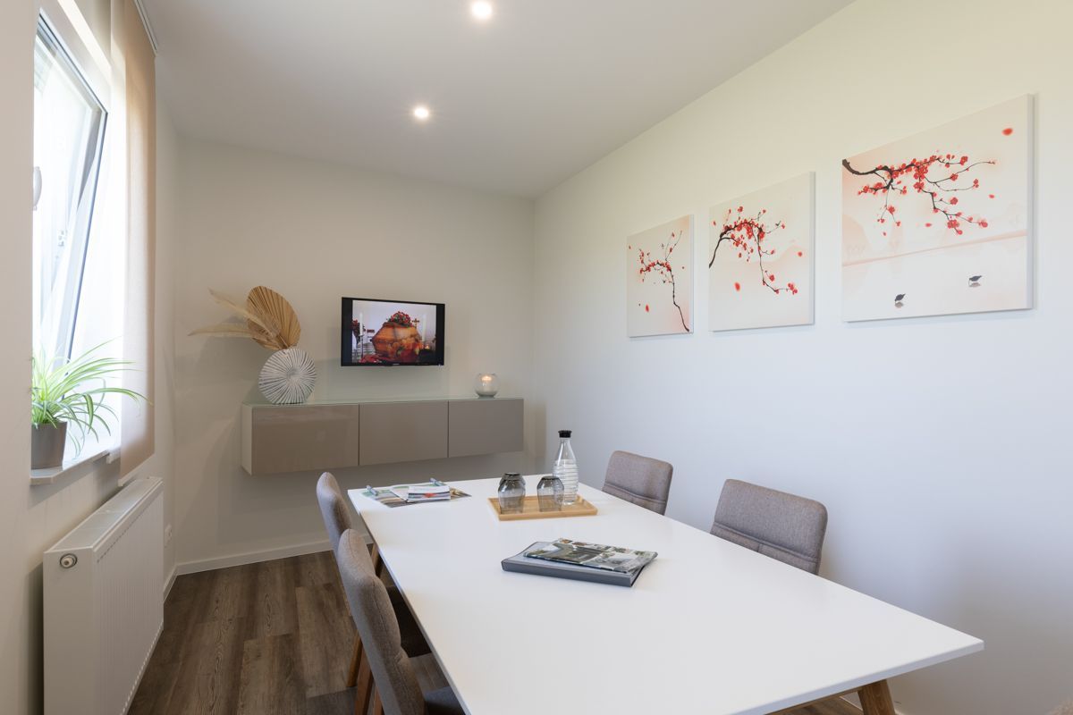 Ein Esszimmer mit Tisch und Stühlen und einem Fernseher an der Wand.