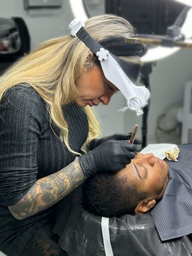 Una mujer se está haciendo un tatuaje en la cara de un hombre.