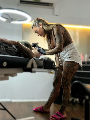 Una mujer se hace un tatuaje en el brazo de un hombre.
