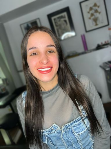 Una mujer con cabello largo sonríe a la cámara en una habitación.
