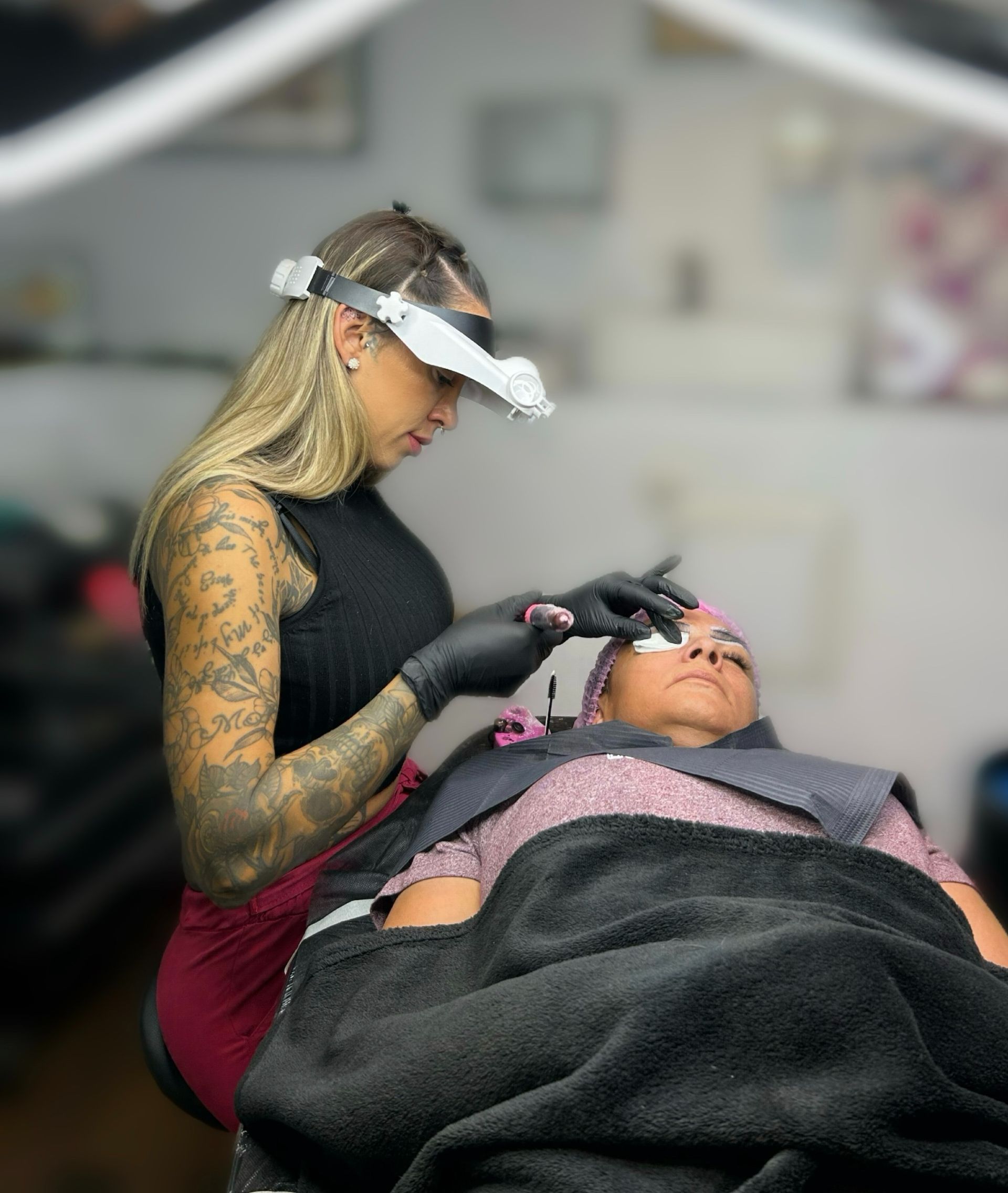Una mujer está aplicando maquillaje a las cejas de una mujer en un salón.